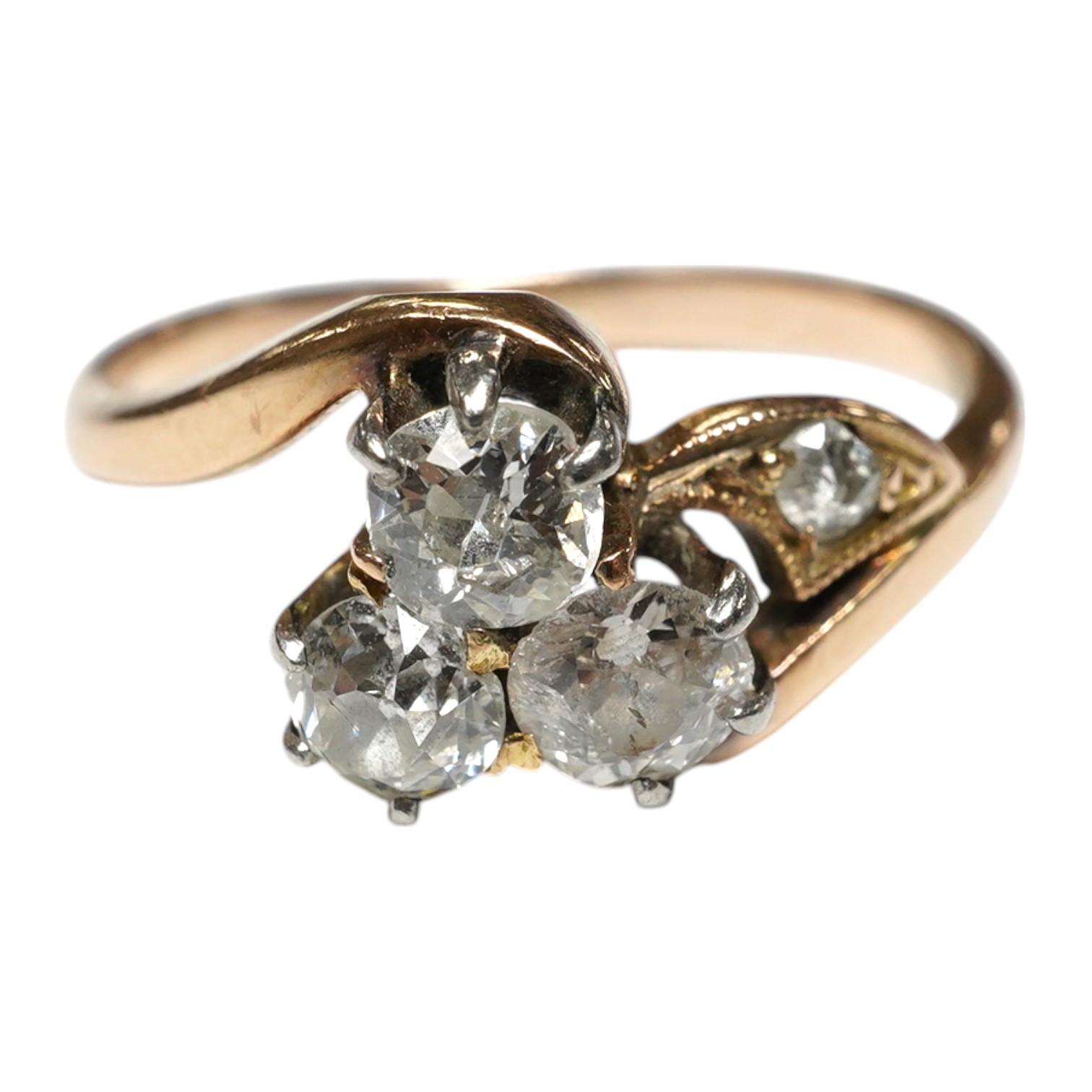 A yellow metal and three stone diamond set crossover ring, with single stone diamond set shoulder, size K, gross weight 2.4 grams. Condition - poor to fair